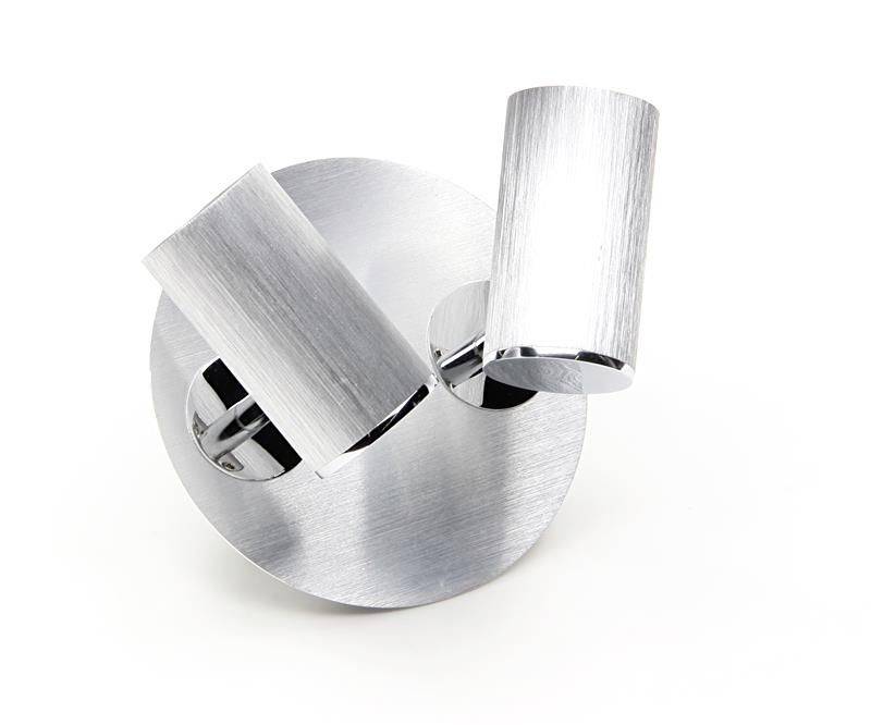 Zwei zylindrische, metallisch glänzende Lampen auf einem runden Sockel, modern und stilvoll gestaltet für Innenraumbereiche.