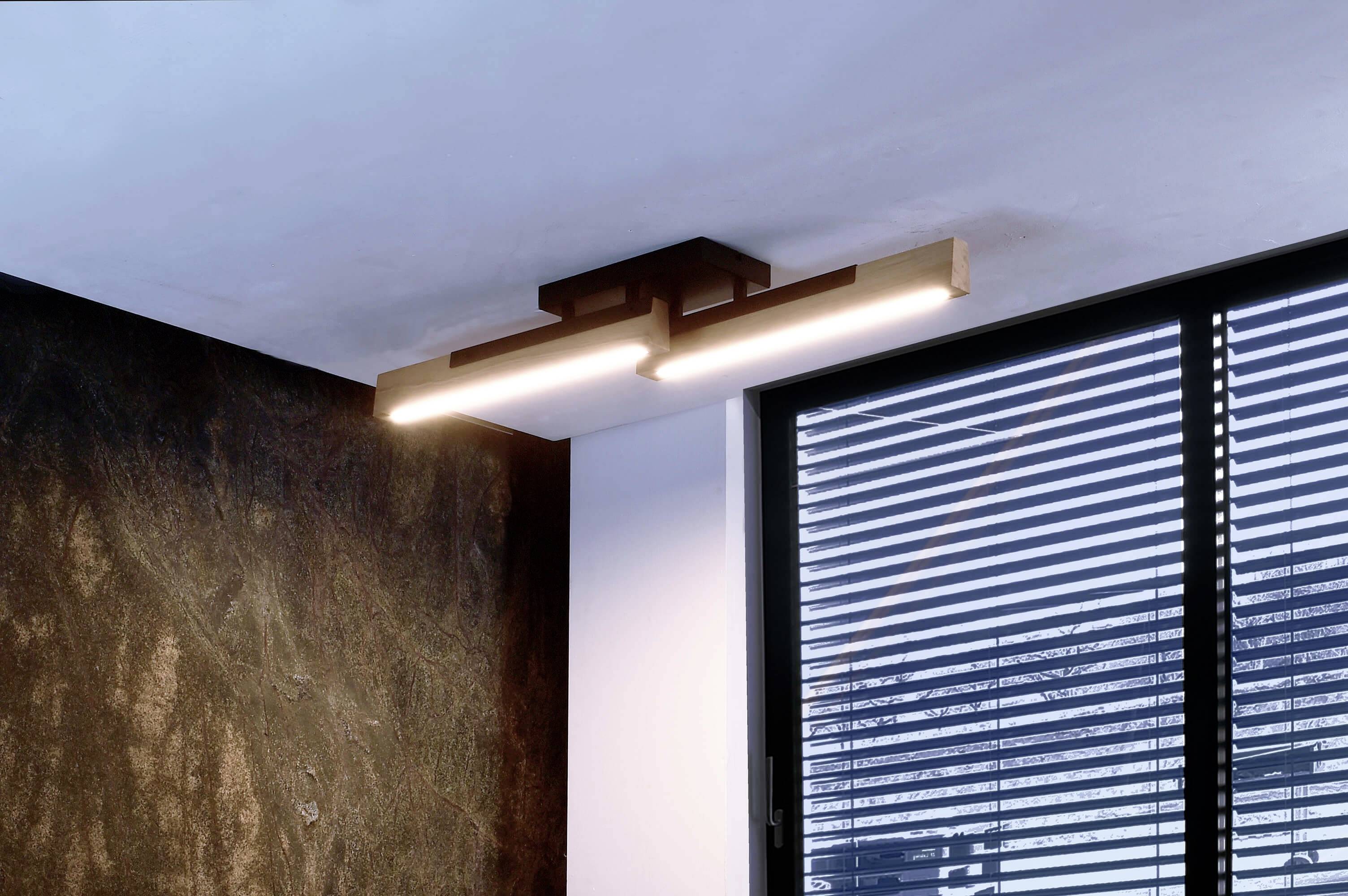 Moderne Deckenleuchte mit rechteckigem Design und LED-Lichtstreifen hängt in einem Raum neben einem Fenster mit Jalousien.