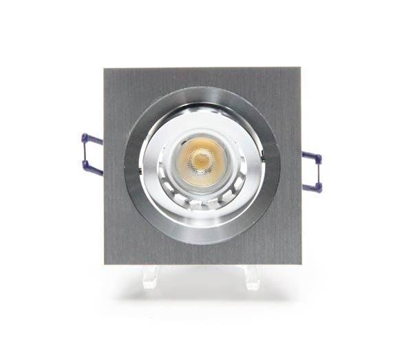 Ein quadratischer Einbaustrahler mit silbernem Rahmen und sichtbarer LED. Er ist frontal abgebildet und befindet sich in einem hellen Raum.