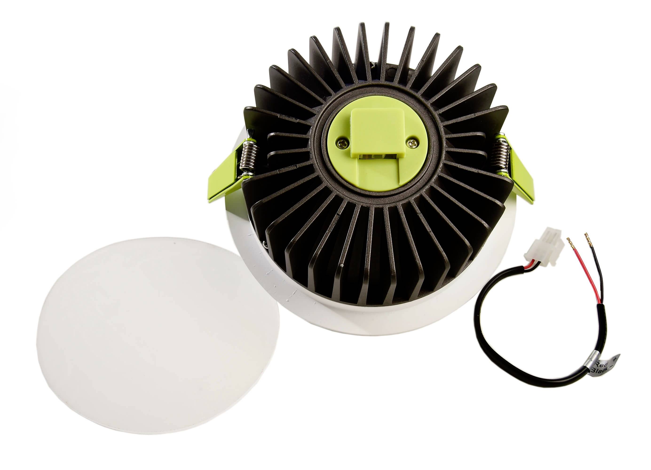 Ein runder LED-Deckeneinbaustrahler mit abgenommenem Diffusor und Steckverbindungskabel. Der Strahler hat ein Kühlrippendesign.