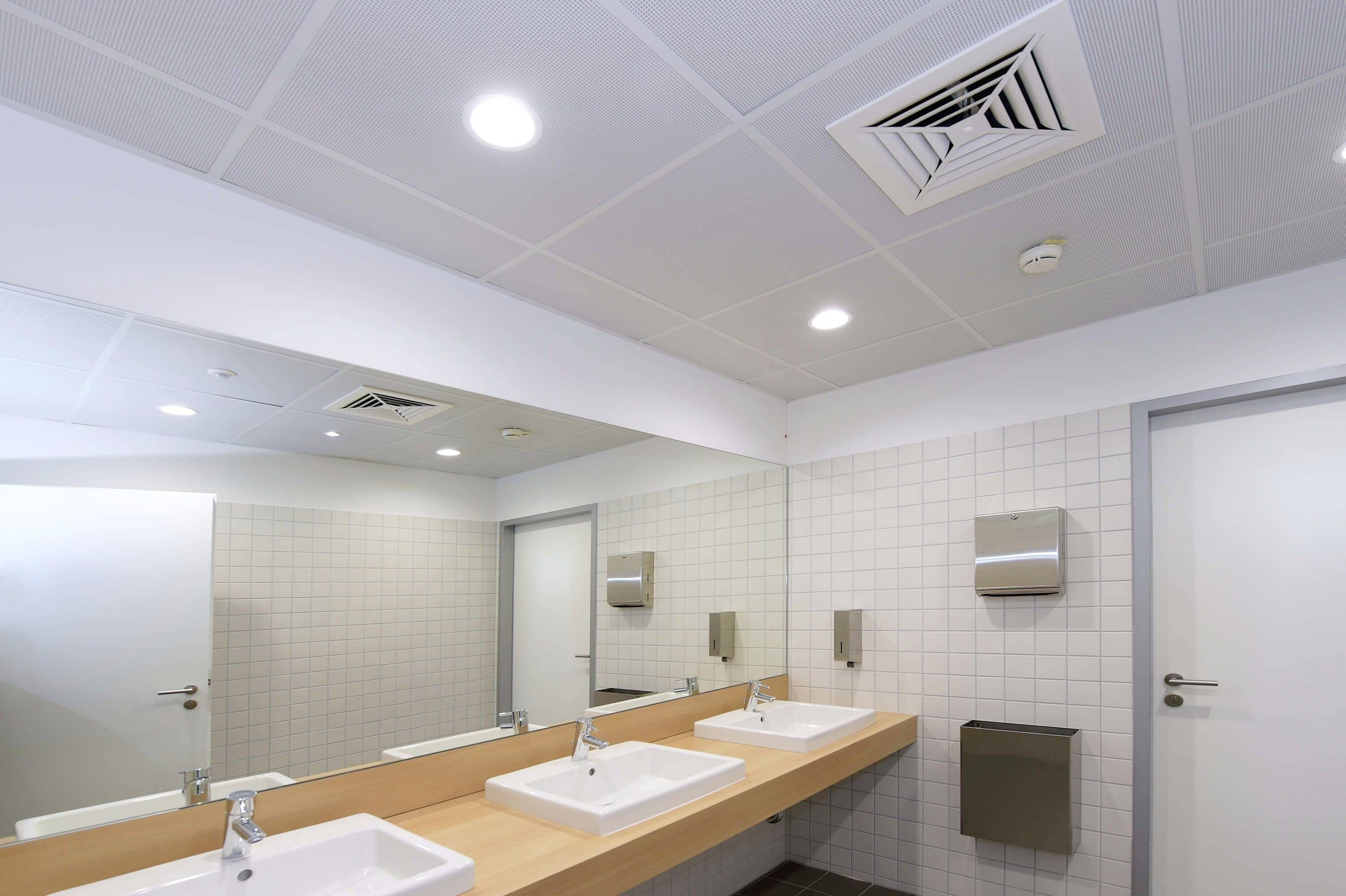 Öffentliche Toilette mit zwei Waschbecken, großen Spiegeln, modernen Armaturen und gefliesten Wänden. Sauber und ordentlich gestaltet.