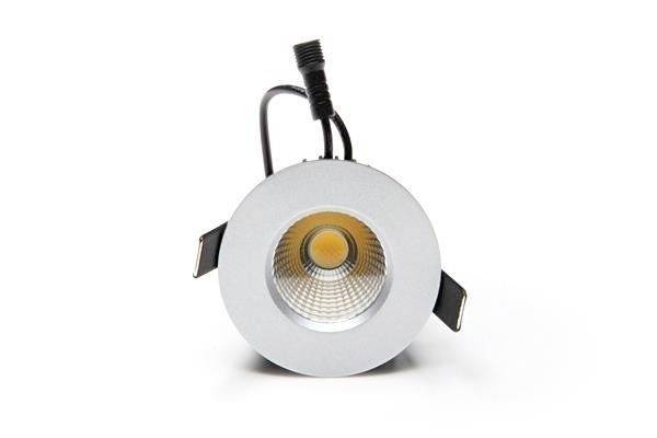 Runde, silberne Deckenleuchte mit fokussiertem, warmweißem LED-Licht in der Mitte, an einem schwarzen Kabel hängend.