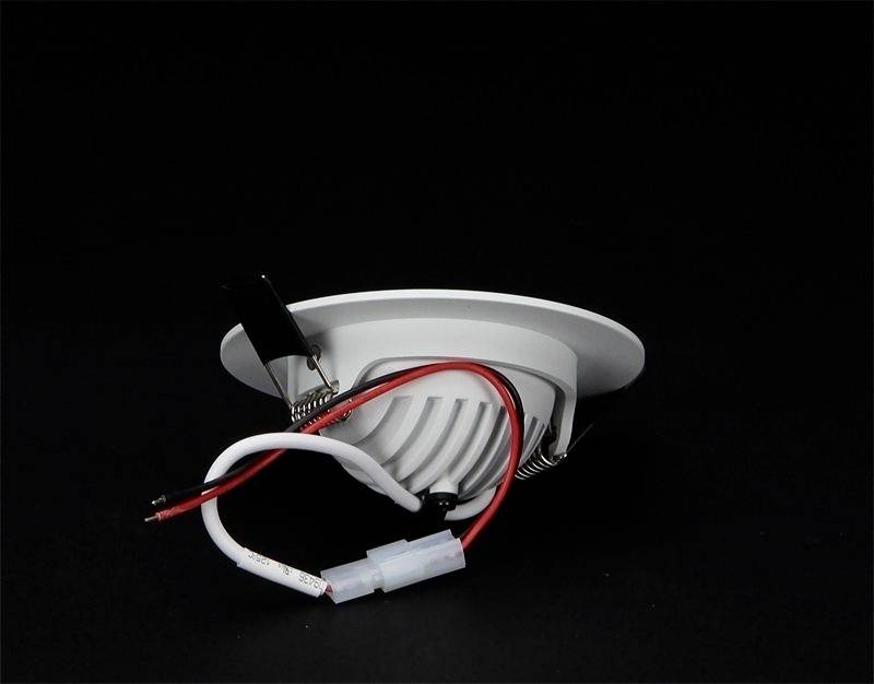 Ein rundes, weißes LED-Downlight mit sichtbaren roten und weißen Drähten auf schwarzem Hintergrund.
