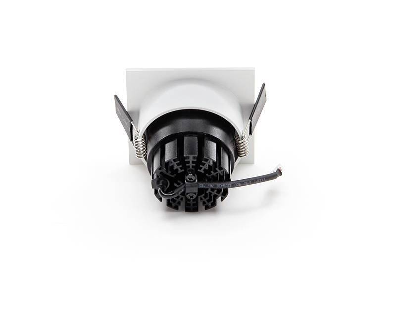 Ein schwarzes, rundes elektrisches Bauteil mit Kabel ragt aus einer weißen Halterung mit Befestigungsklammern heraus.