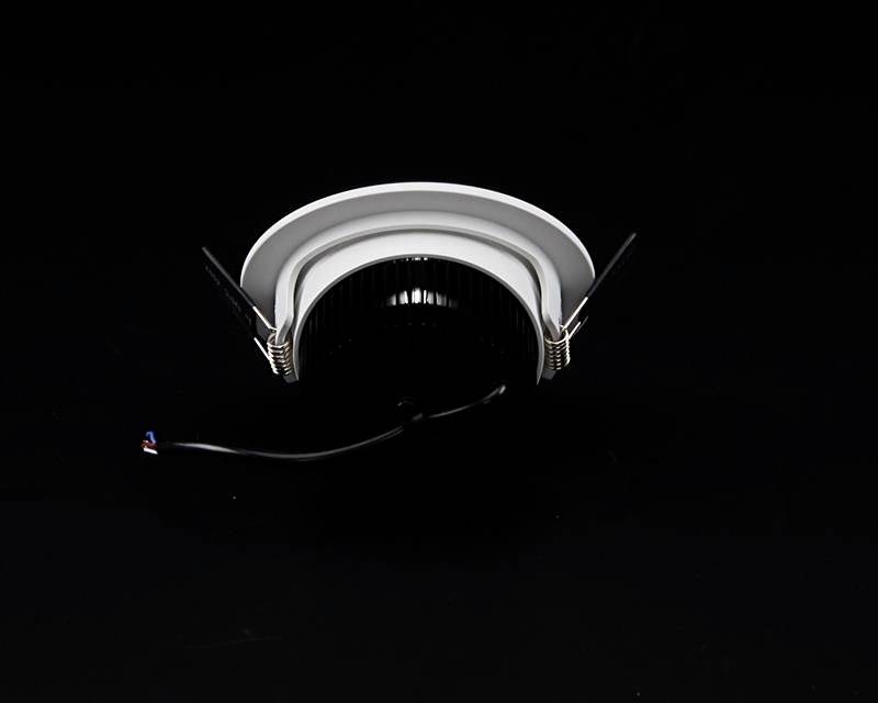 Schwarzer runder LED-Deckenstrahler vor dunklem Hintergrund, mit zwei Halteklammern und einem herausragenden Kabel.