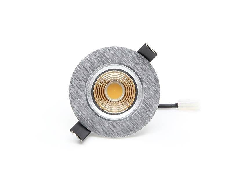 Runde LED-Leuchte mit grauem Gehäuse und kupferfarbener Linse, eingebauter Kabelanschluss, aus der Vogelperspektive fotografiert.