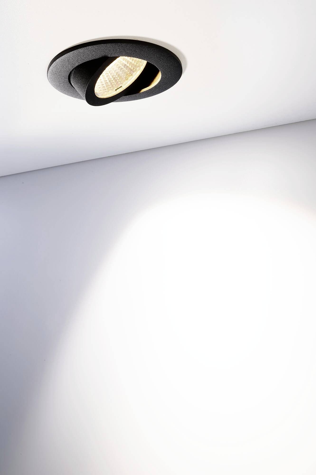 Deckenleuchte mit modernem Design, wirft sanftes, warmweißes Licht auf eine weiße Decke, sorgt für eine stimmungsvolle Beleuchtung.