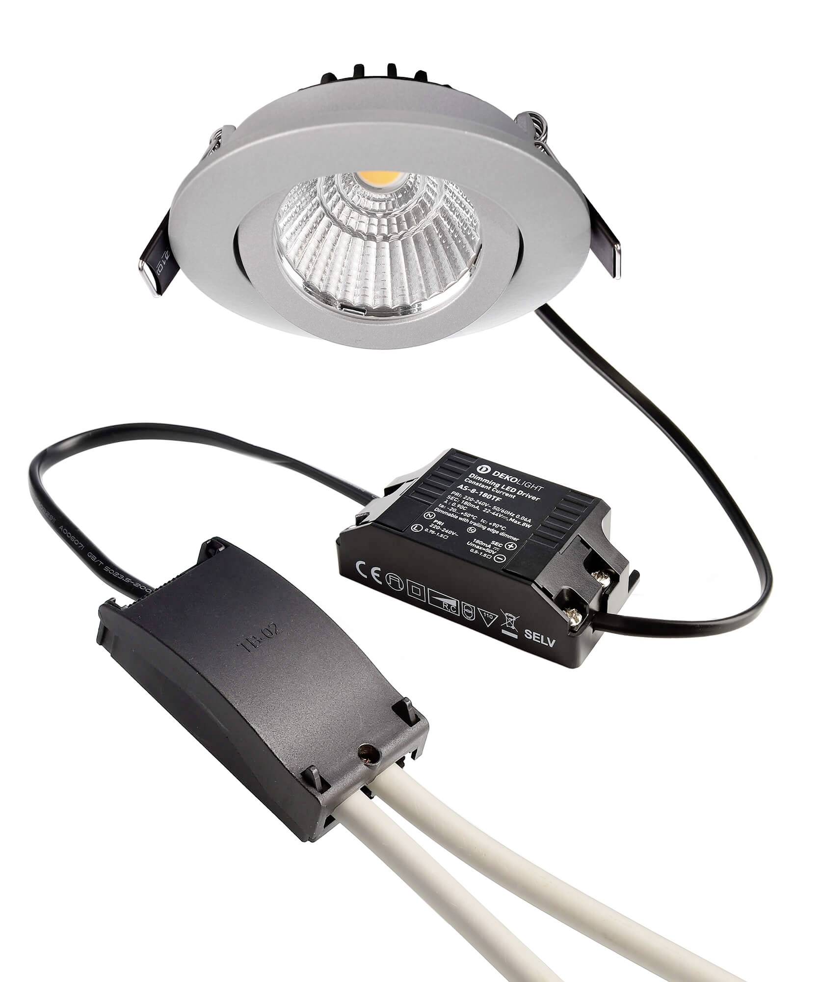 Abbildung eines runden LED-Deckeneinbaustrahlers mit silbernem Rahmen, verbunden mit einem schwarzen Transformator und Kabeln.