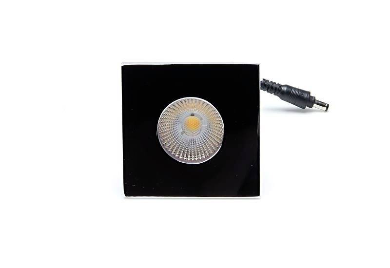 Quadratisches, schwarz-glänzendes LED-Modul mit zentralem Leuchtelement und angeschlossenem Kabel, frontal abgebildet.
