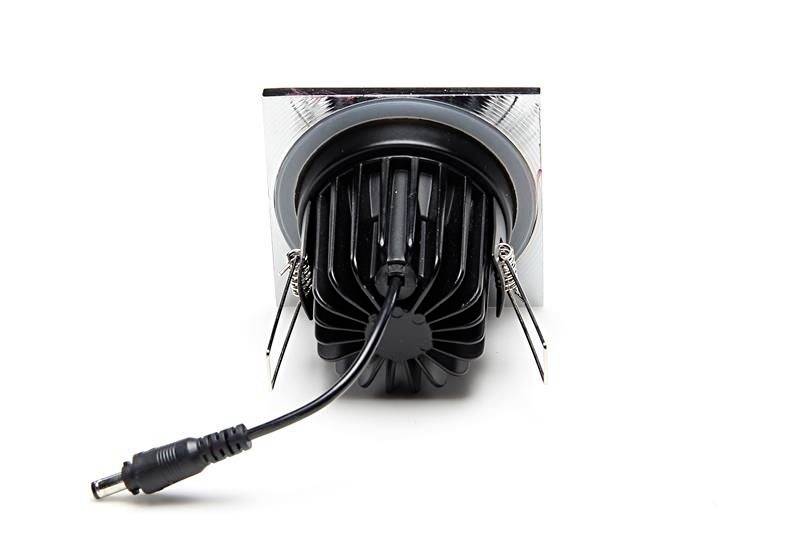 Ein quadratischer, verstellbarer LED-Downlight-Sockel von hinten, mit einem angeschlossenen Stromkabel, umgeben von einem silbernen Rahmen.