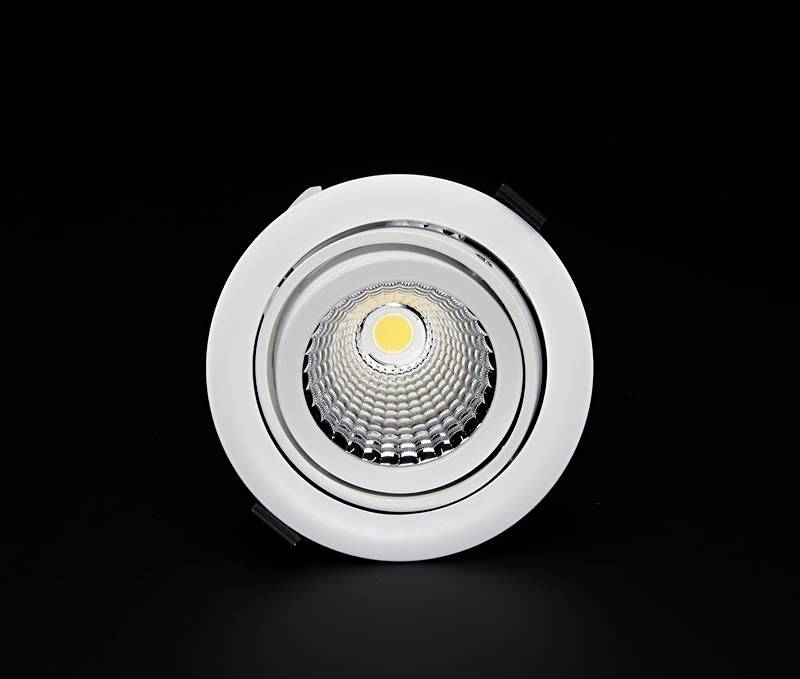 In die Decke eingebauter LED-Spot mit weißem Rahmen, leuchtet in der Mitte, kontrastiert vor schwarzem Hintergrund.