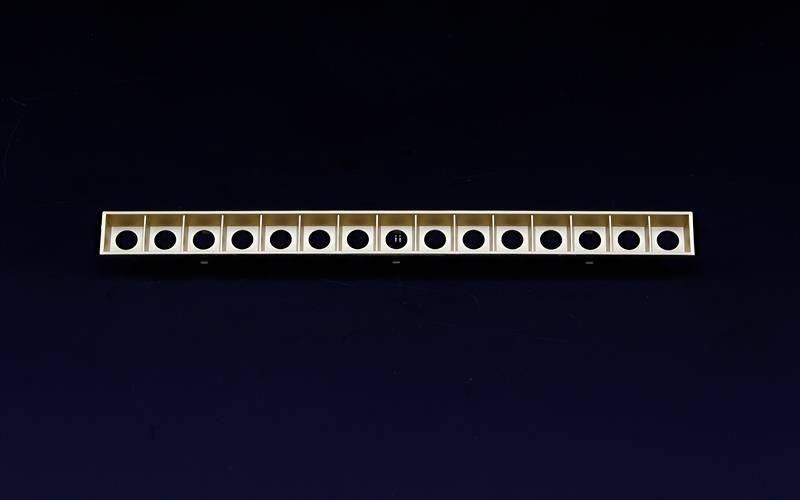 '13-teiliges Instrument in Reihe mit Löchern, glänzende Oberfläche, schwarzer Hintergrund'