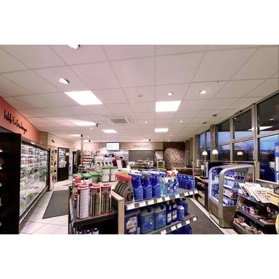 Ein gut beleuchteter Supermarkt mit Regalen voller Reinigungsmittel, Snacks und Getränken. An der linken Wand steht ein Tiefkühlregal.