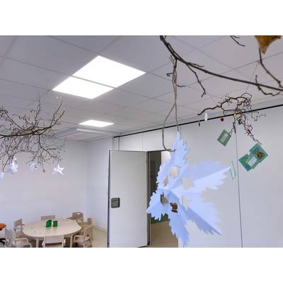 Ein heller Raum mit einem runden Tisch und kleinen Stühlen. An der Decke hängen dekorative Äste mit Papiersternen und Karten.