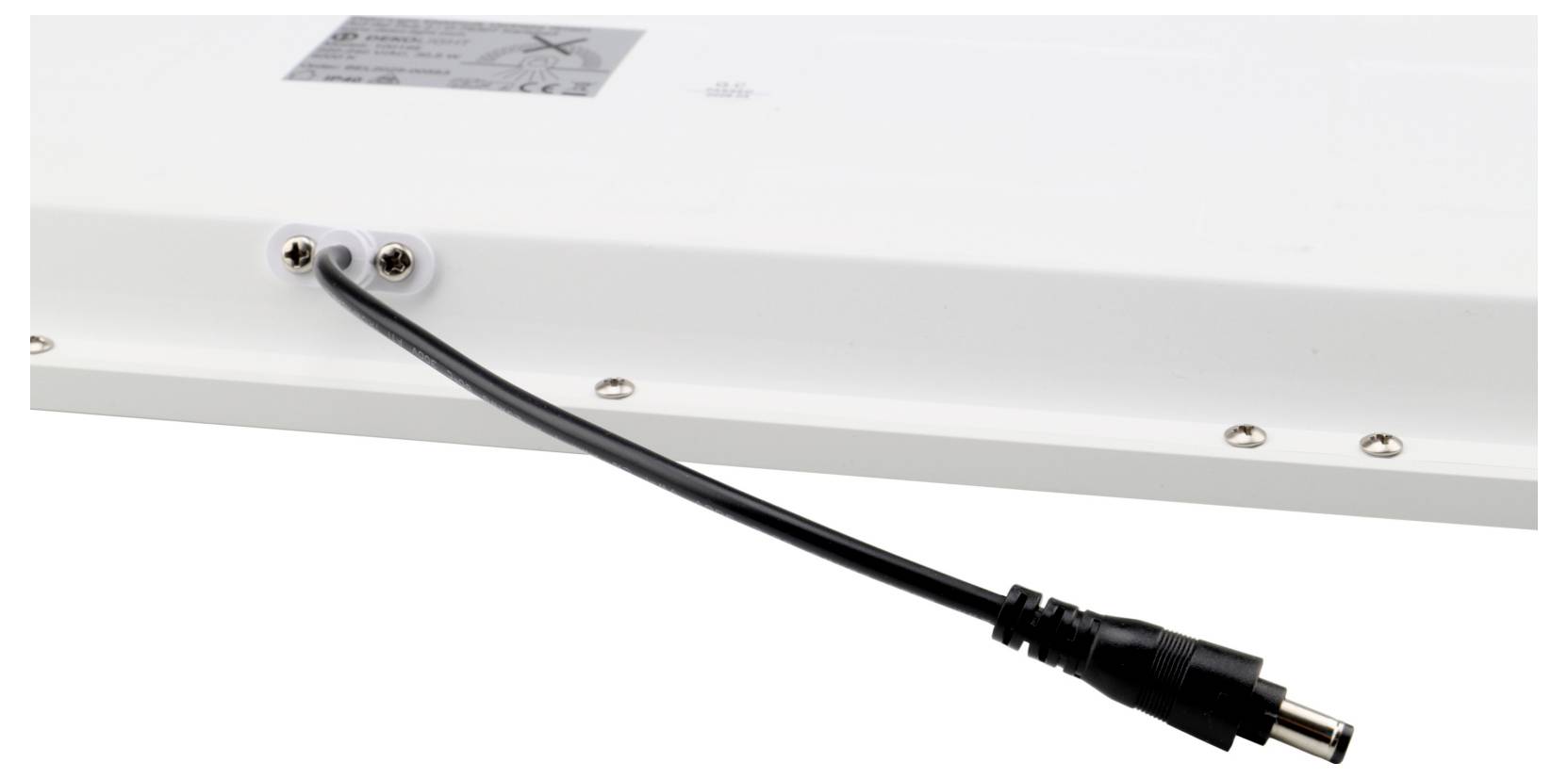 Nahaufnahme eines schwarzen Netzkabels mit einem DC-Hohlstecker, das von einem weißen elektronischen Gerät ausgeht.