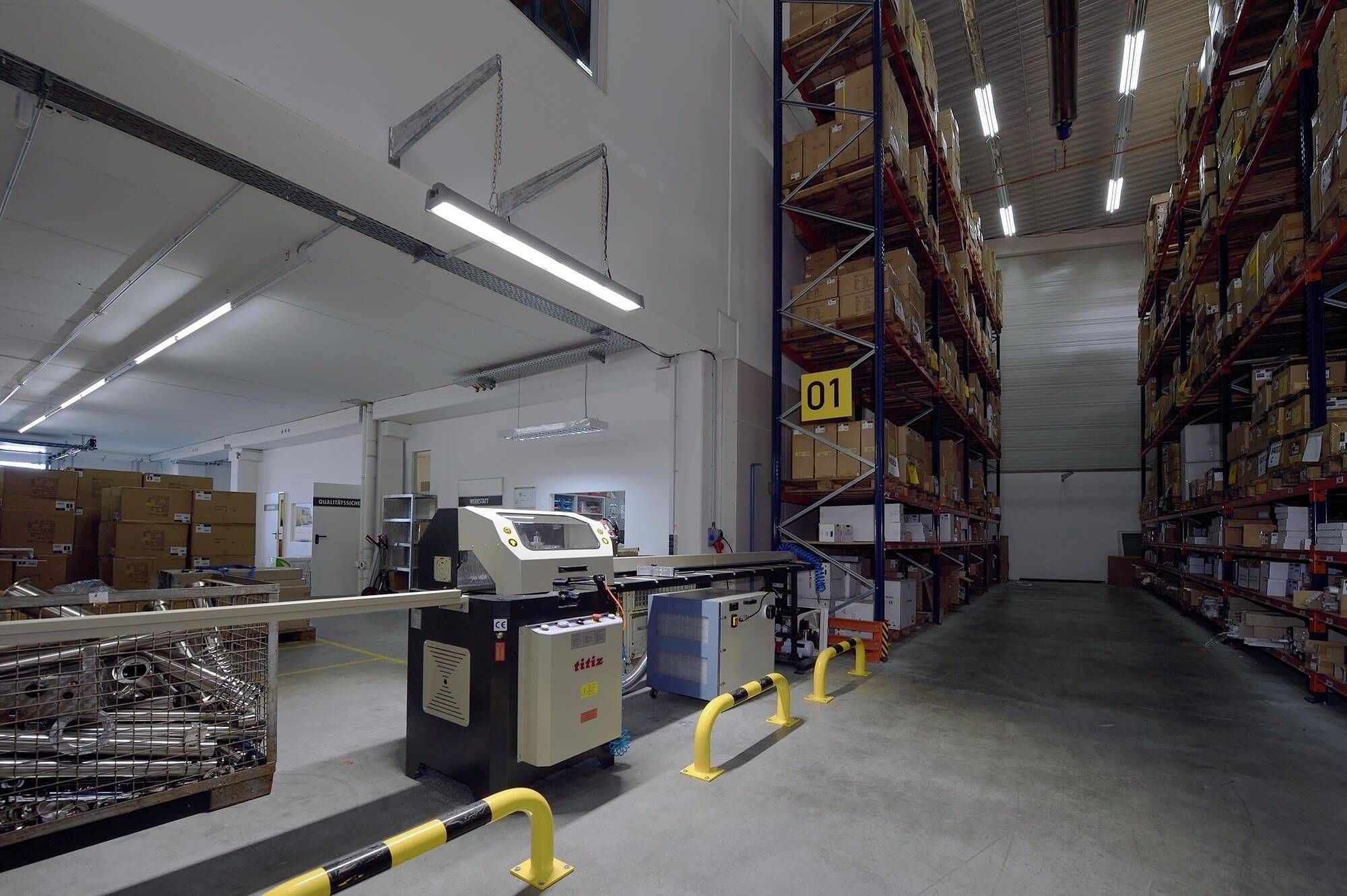 Ein Lagerhaus innen mit langen Regalen voller Kartons auf Paletten. Eine Verpackungsmaschine befindet sich im Vordergrund.