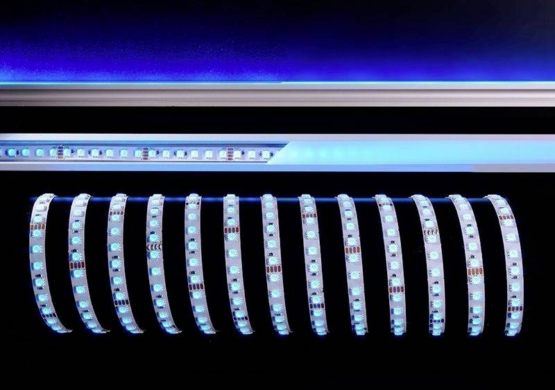 LED-Leuchtbänder in blauer Farbe, ausgerollt und parallel nebeneinander auf dunklem Hintergrund. Oben im Bild ist ein leuchtendes Band.