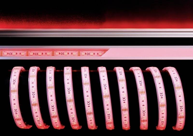 Leuchtende rote LED-Lichtstreifen, teilweise aufgerollt, in einem dunklen Raum platziert. Sie erzeugen ein intensives, gleichmäßiges Licht.