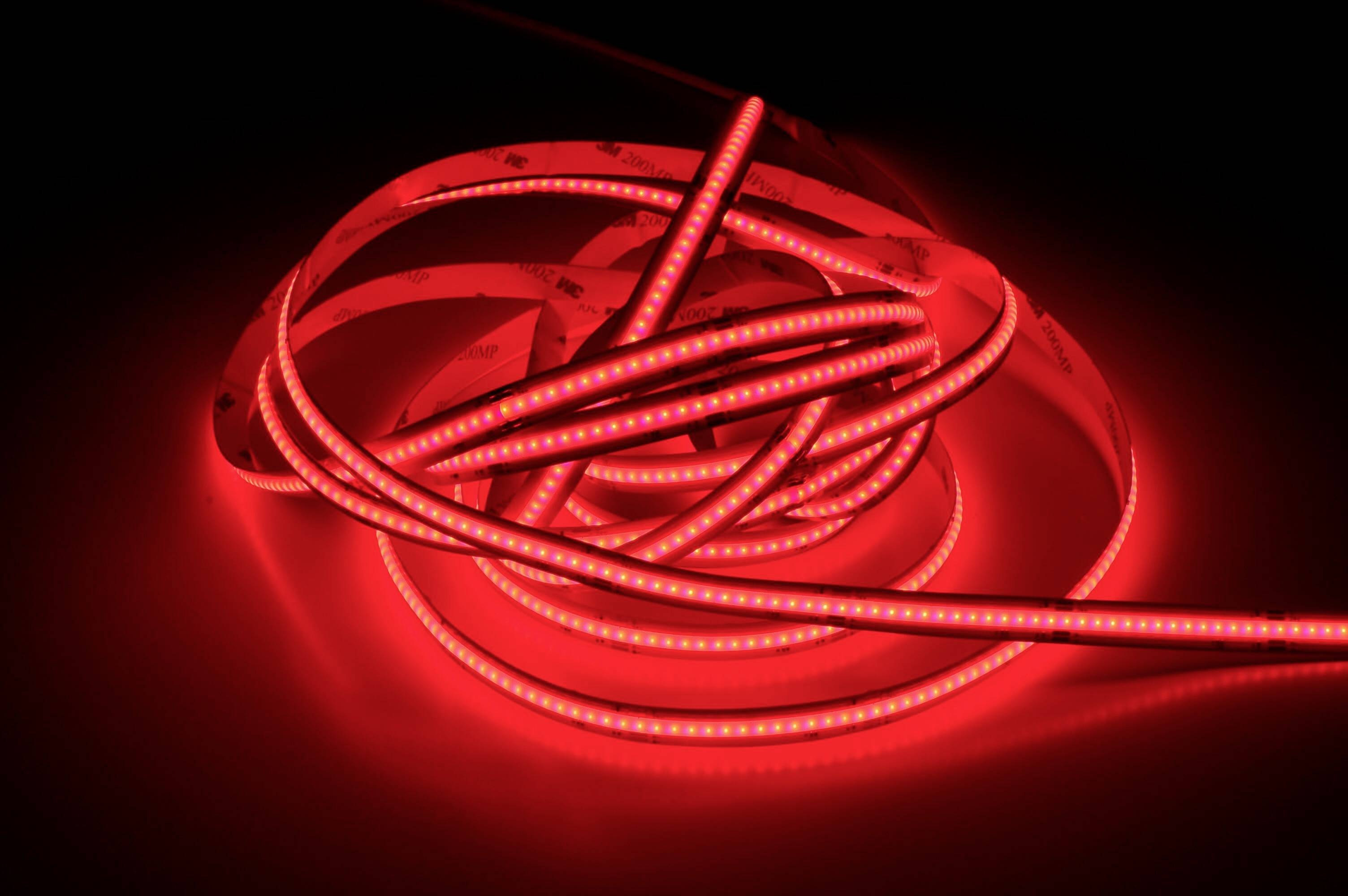 Ein rotes LED-Lichtband liegt in Schleifen auf einer schwarzen Oberfläche und leuchtet intensiv.