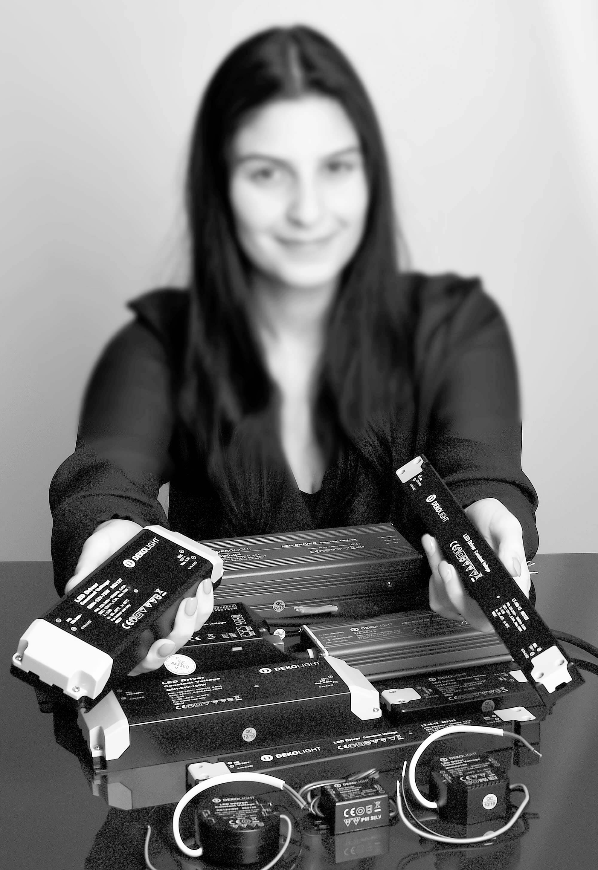 Eine Person hält elektronische Geräte in den Händen, weitere Geräte liegen auf dem Tisch. Die Geräte scheinen technisch und kompakt zu sein.