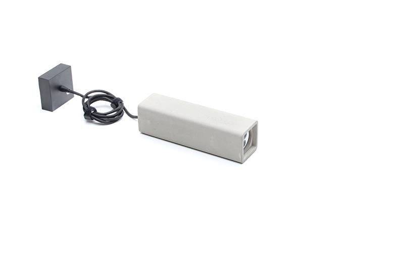 Ein rechteckiger, grauer Gegenstand mit Kabel und quadratischer Basis, möglicherweise ein technisches Gerät oder Ladegerät-Anhang.