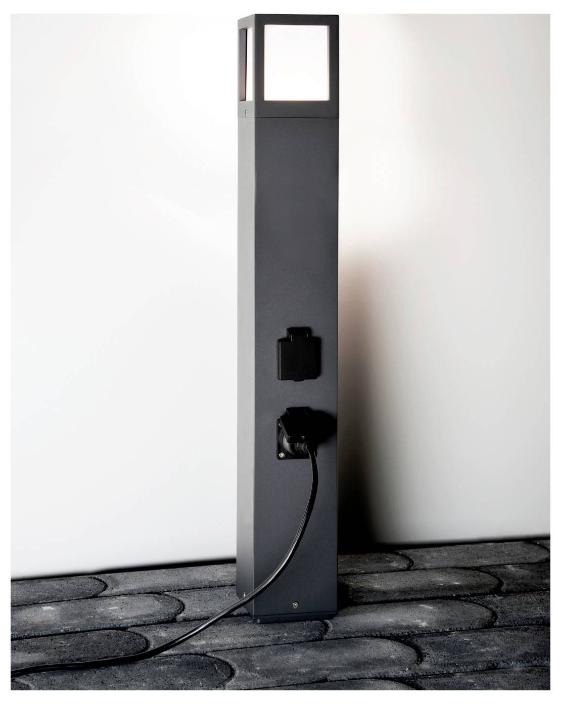 Hohe Außen-Stromsäule mit beleuchteter Oberseite und Steckdose, ein schwarzes Kabel ist unten eingesteckt.