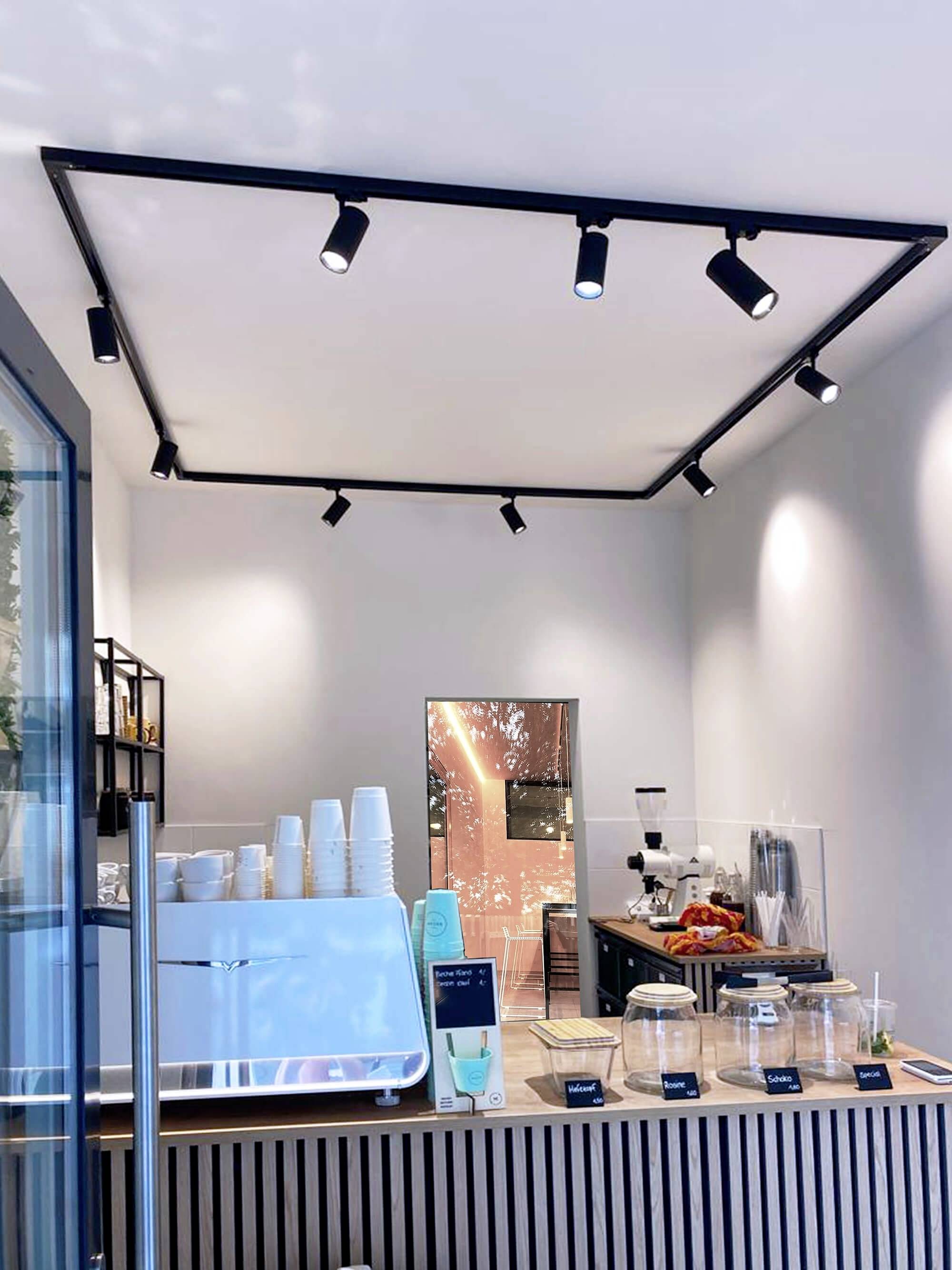 Moderner Café-Interieur mit Kaffeemaschine, Tassen und Snacks in gläsernen Behältern auf einem Holztheken. Dezente Beleuchtung.