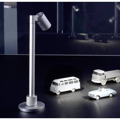 Ein Miniaturmodell zeigt einen beleuchteten Van und zwei Autos. Daneben steht eine moderne Lampe. Im Hintergrund unscharfe andere Autos.