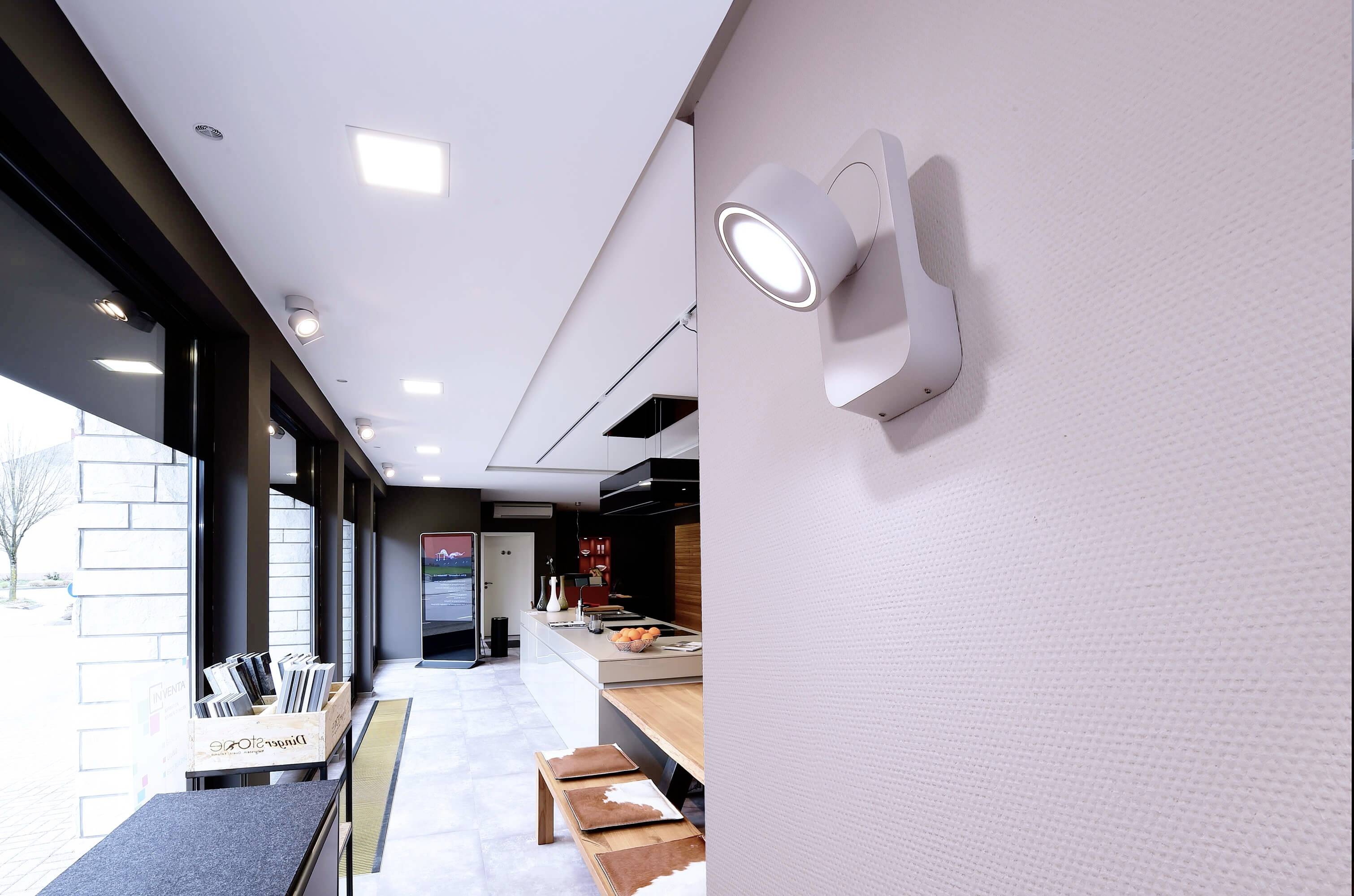 Eine moderne Küche mit weißem Kühlschrank und Holzarbeitsflächen. An der Wand ist eine leuchtende weiße Lampe angebracht. 