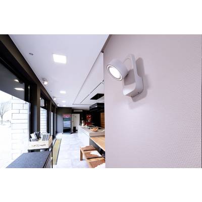 Eine moderne Küche mit weißem Kühlschrank und Holzarbeitsflächen. An der Wand ist eine leuchtende weiße Lampe angebracht.