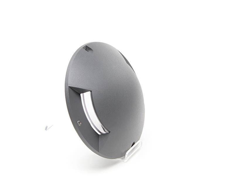 'Runde graue LED-Bodenleuchte mit seitlichem Lichtauslass auf weißem Hintergrund.'