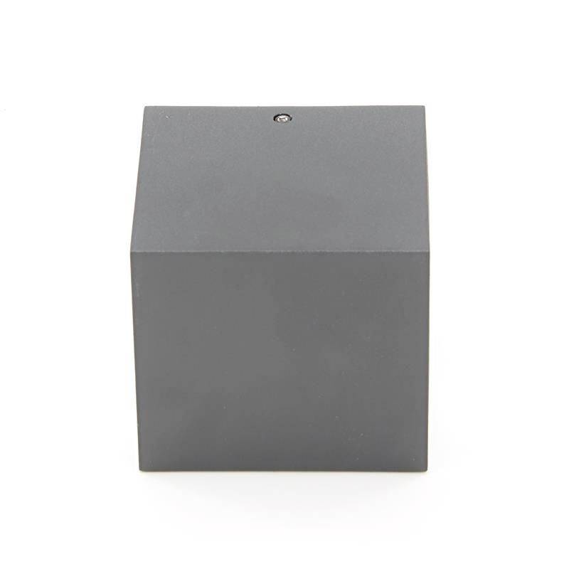 Grauer Würfel aus Metall mit einer kleinen Schraube an der Oberseite, minimalistisch gestaltet, steht auf einer hellen Fläche.