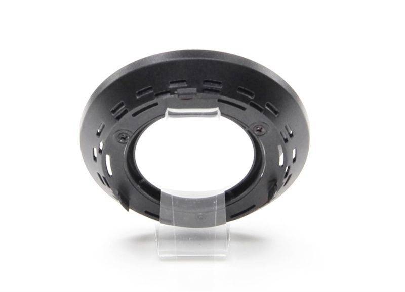 Ein schwarzer, runder Kunststoffring mit Schlitzen, auf einem transparenten Kunststoffständer in der Mitte platziert.