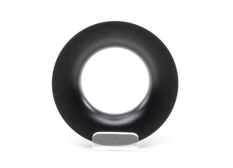 Schwarzer, flacher Ring mit kreisförmigem Loch in der Mitte auf transparentem Ständer; minimalistische, moderne Skulptur.