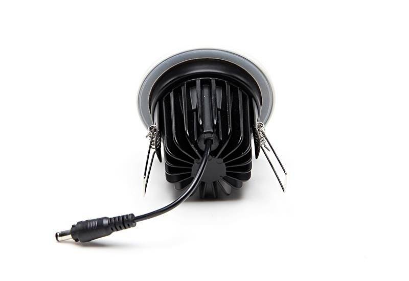 Ein schwarzer, runder LED-Einbauspot mit Kühlrippen, Draht und Stecker, seitlich gezeigt. Geeignet für Deckenmontage.