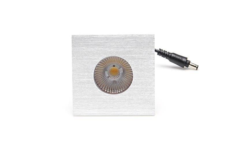 Quadratische LED-Einbauleuchte aus gebürstetem Metall mit sichtbarer Linse und einem Stromanschlusskabel rechts.