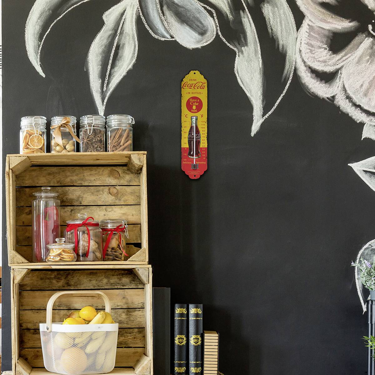 Ein Regal mit Einweckgläsern voller Gewürze und Früchten steht vor einer schwarzen Wand mit Kreidemalerei und einem Coca-Cola-Werbeschild.