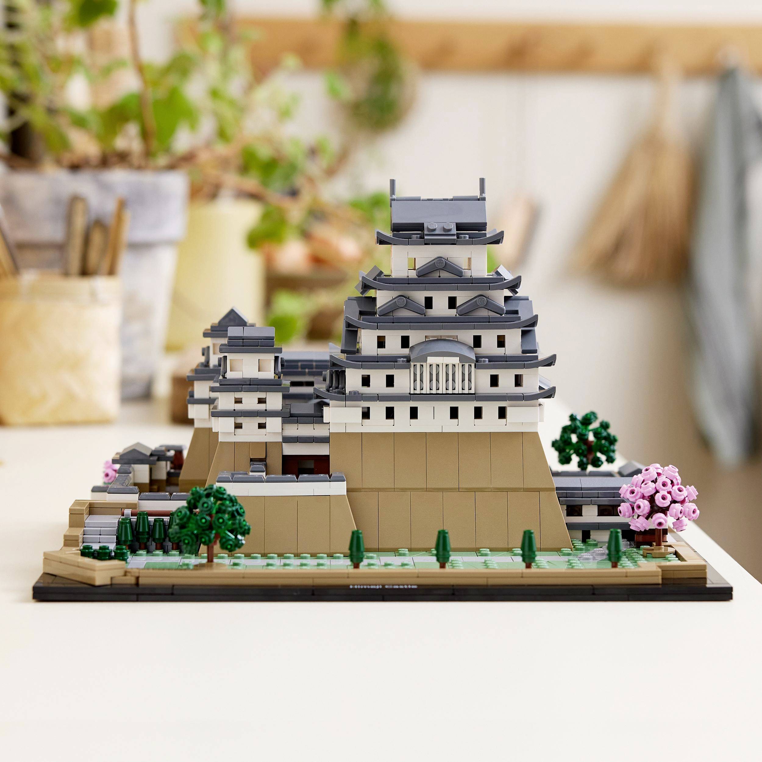 Lego-Modell des Himeji-Schlosses auf einem Tisch, umgeben von Pflanzen. Detaillierte Nachbildung berühmter japanischer Architektur.