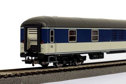 Ein Modellbahn-Personenwaggon auf einem Gleis, dunkelblau mit beigem Streifen, zeigt Details wie Fenster und Räder.