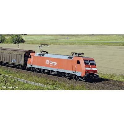 Ein roter Güterzug der DB Cargo fährt auf Schienen durch ländliche Umgebung bei Tageslicht. Links im Bild befindet sich ein Güterwaggon.