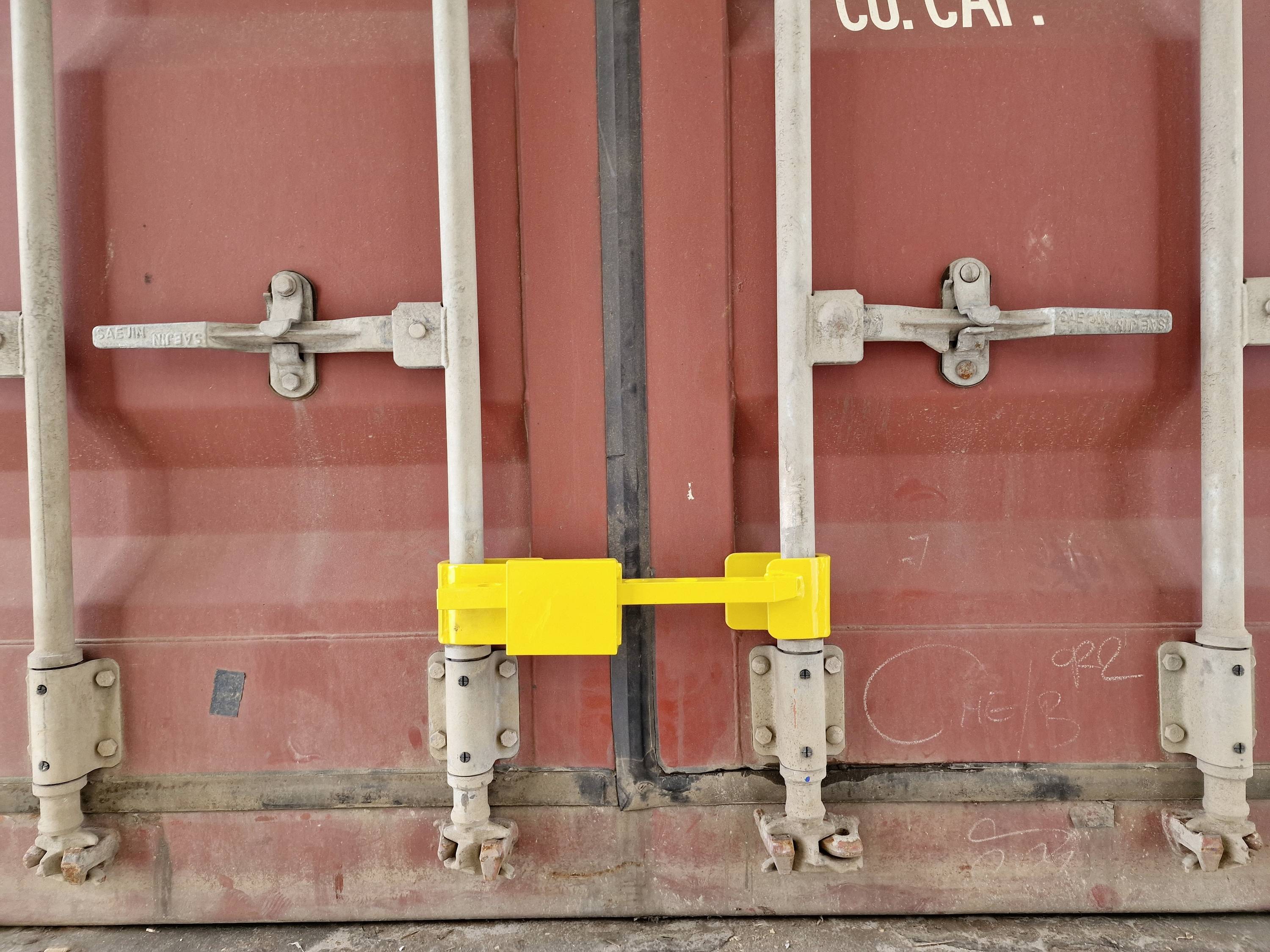 Ein roter Seecontainer mit gelbem Schloss an der Doppeltür. Die Umgebung wirkt industriell.