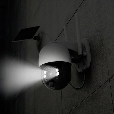 Schwarze Sicherheitskamera mit Nachtsicht-LEDs, an einer grauen Wand befestigt, und einem angeschlossenen Solarpanel.