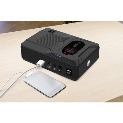 Eine tragbare Powerbank mit mehreren Anschlüssen auf einem Tisch. Ein Smartphone ist über ein Kabel verbunden und wird geladen.