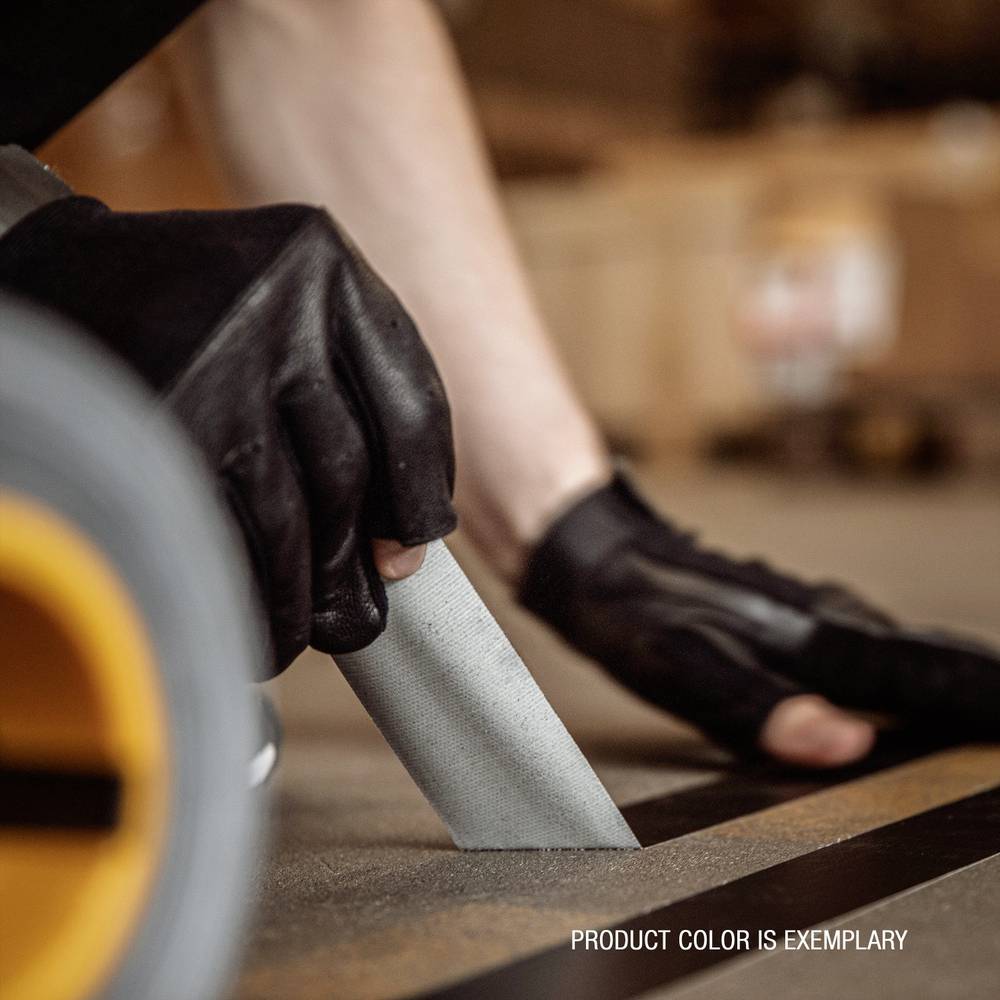 Person trägt schwarze Handschuhe und benutzt ein Cuttermesser, um etwas auf dem Boden abzuschneiden. Text: 'PRODUCT COLOR IS EXEMPLARY'.