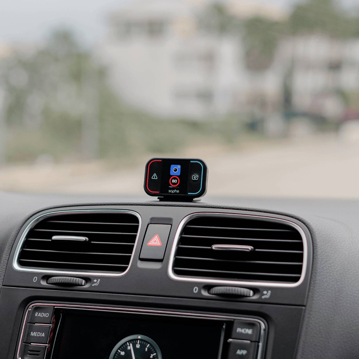 Ein kleines elektronisches Gerät mit Display ist auf dem Armaturenbrett eines Autos montiert. Es zeigt Symbole und Farben.