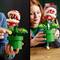 Eine Person hält ein Lego-Modell einer Pflanzenfigur mit großen Zähnen und roten Köpfen in einem grünen Rohr.