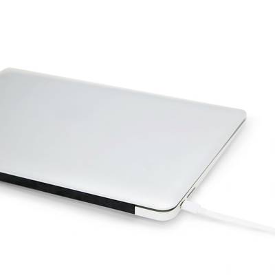 Ein zugeklappter, silberner Laptop wird über ein Kabel aufgeladen. Der Hintergrund ist weiß.