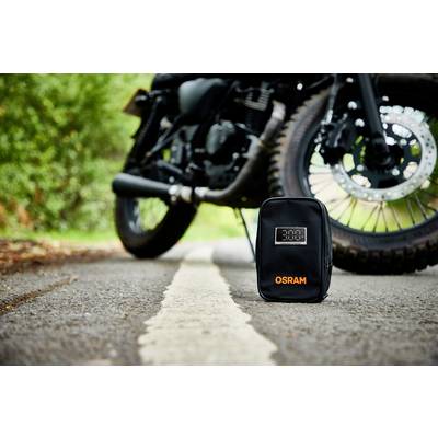'OSRAM'-Tasche liegt auf einer Straße im Fokus, im Hintergrund ein Motorrad.