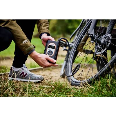 Eine Person pumpt ein Fahrradreifen auf, indem sie ein digitales Gerät verwendet, das 50 PSI anzeigt.