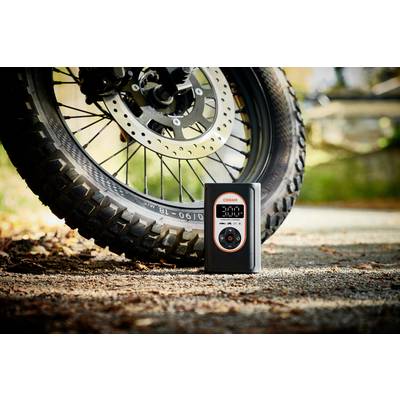 Motorradreifen auf Asphalt, daneben ein digitaler Reifendruckmesser von Osram, der 3.00 Bar anzeigt. Umgebung herbstlich.